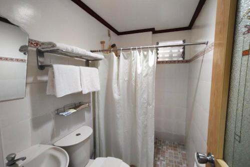 a bathroom with a toilet and a shower curtain at Shenna's Beach Resort Boracay in Boracay