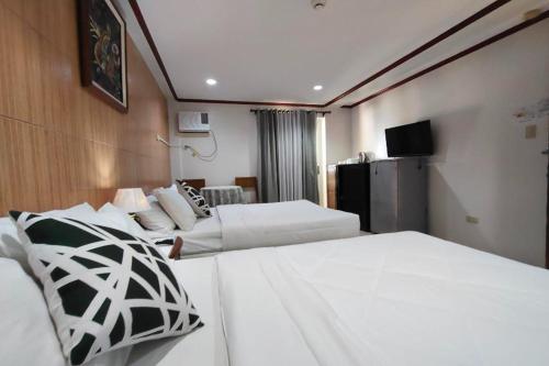 a hotel room with two beds and a television at Shenna's Beach Resort Boracay in Boracay