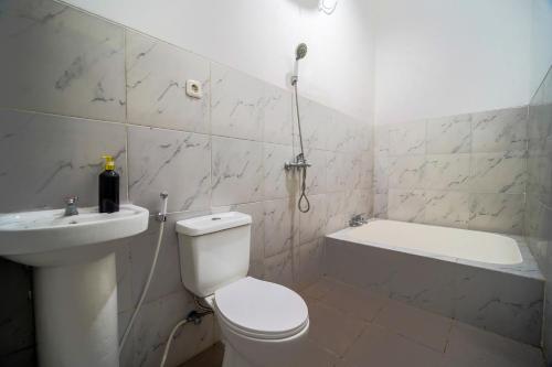 a bathroom with a toilet and a sink and a bath tub at Timeless Sevilla Luxe in Ngemplak