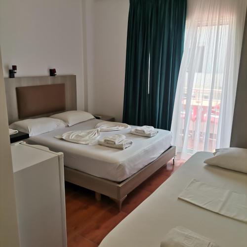 a bedroom with two beds and a large window at Koli Apartments in Ksamil