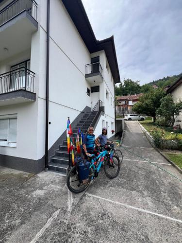 two people on a bike parked outside a building at Apartmani Gala Foča in Foča