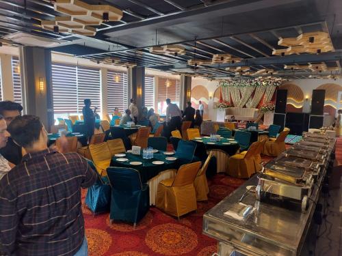 a group of people sitting at tables in a restaurant at Vani Hotel Golden Petals in Una