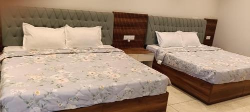 a bedroom with two beds with white sheets and flowers at Vani Hotel Golden Petals in Una