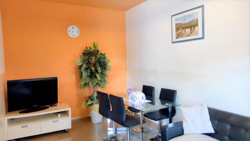 a living room with a table with chairs and a television at Spacious Apartment with Pool in M'bour - 100 m² in Mbour