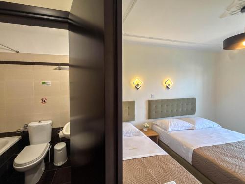 a room with two beds and a toilet and a sink at Celeste Blu Suites & Rooms in Paralia Katerinis