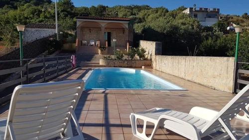 two chairs and a swimming pool with a house at Beautiful Villa in Caccamo + Pool in Caccamo