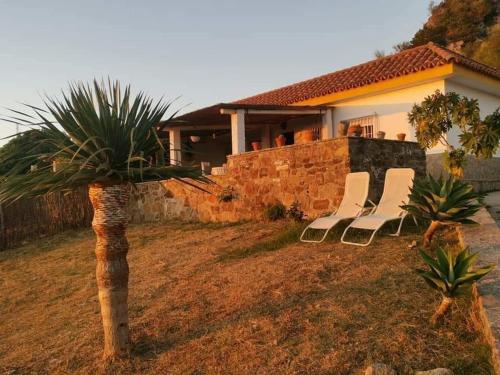 a group of chairs sitting in front of a house at Charming house with sea and mountain views in El Chaparral in EL Chaparral