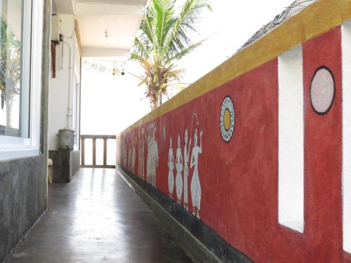 a red and white wall in a building with palm trees at Mountain Wave Hotel and Surfshop in Hikkaduwa