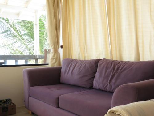 a purple couch in a living room with a window at Mountain Wave Hotel and Surfshop in Hikkaduwa