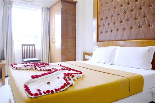 a hotel room with a bed with red flowers on it at TR Residency in Pondicherry