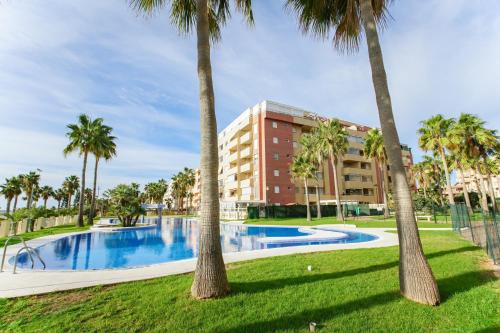 a pool with palm trees in front of a building at Modern apartment in Roquetas de Mar with sea view in Roquetas de Mar