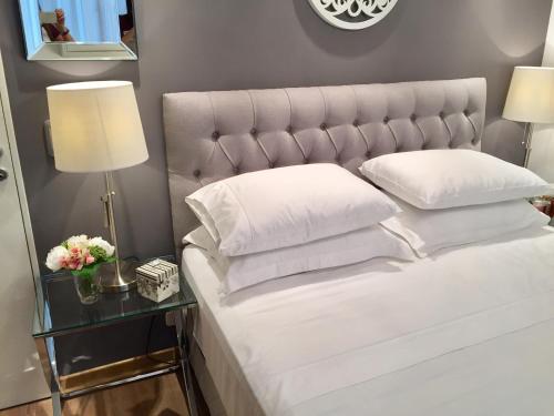 a bed with white pillows and a table with a lamp at Luxury Apartment Tagle with flexible Chek in or Check out in Buenos Aires
