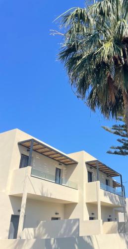 a building with a palm tree in front of it at Nikos Apartments & Studios in Plakias