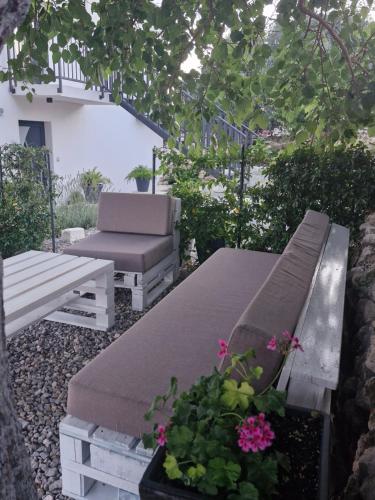 two benches and a chair in a garden with flowers at Rural home Basin dvor with jacuzzi in Vinišće
