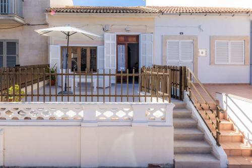 a house with a gate and stairs with an umbrella at House by the sea in Can Picafort with terrace in Can Picafort
