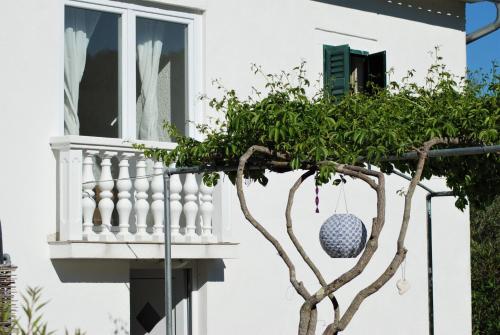 a white house with a tree and a window at Spacious house in Lukoran with sea view in Lukoran