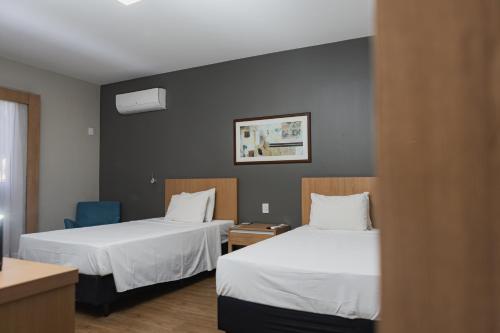a hotel room with two beds and a blue chair at Comfort Suites Flamboyant Goiânia in Goiânia