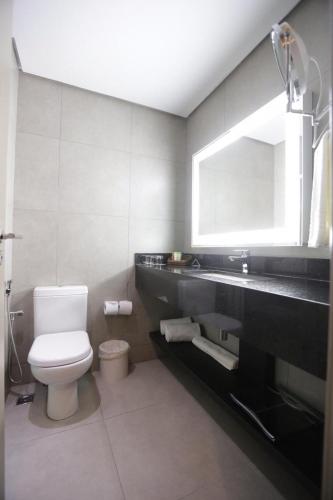 a bathroom with a toilet and a sink and a mirror at Comfort Suites Flamboyant Goiânia in Goiânia