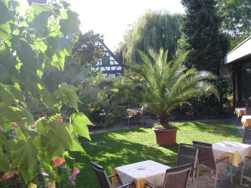 a garden with tables and chairs and palm trees at Gasthaus zum Rössel Lichtenau in Scherzheim