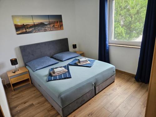 a bedroom with a bed with blue pillows and a window at Apartmani Janja in Krk