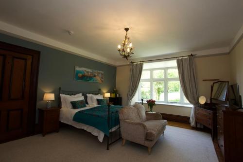 a bedroom with a bed and a chair and a chandelier at Costislost House in Wadebridge