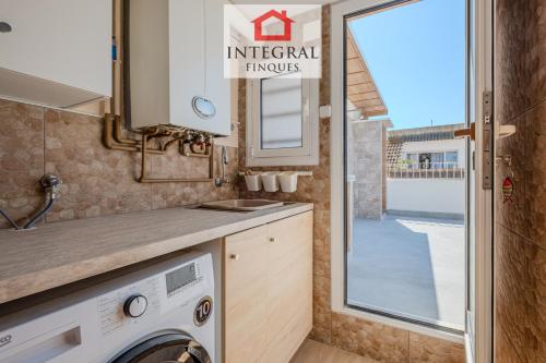 a kitchen with a washer and dryer and a window at Casa Terral in Palamós