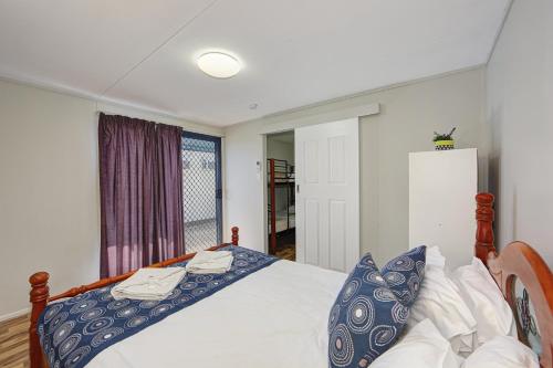 a bedroom with a bed with blue pillows and a window at Alva Beach Tourist Park in Alva