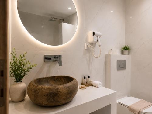 a bathroom with a large stone sink and a mirror at Pattys Desing Suites- Private Hot Tub with yard- Fira Center in Firostefani