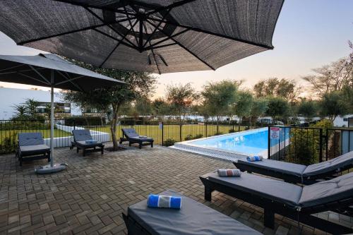 a patio with an umbrella and a swimming pool at Karoo Retreat- Self Catering Villas and Guest House in Oudtshoorn