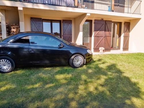 a black car parked in the grass in front of a house at Appartement charmant avec vue sur lac et montagne – 75 m² in Fontrabiouse