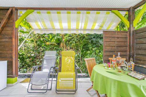 a table with a green table cloth on a patio at Bungalow charmant à Rivière-Salée avec terrasse privée in Rivière-Salée