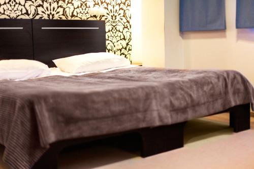 a large bed with a black headboard and white pillows at Hotton Hotel in Gdynia
