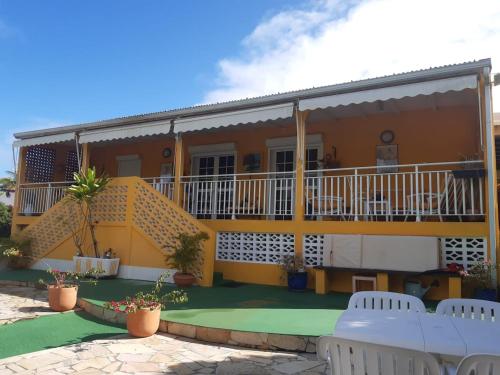 a yellow house with a balcony and chairs at Villa élégante à Sainte-Anne avec piscine privée ouverte toute l'année in Sainte-Anne