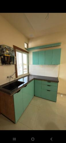 a kitchen with green cabinets and a sink at Cube Stay in Bhopal