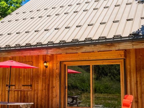 a metal roof on a cabin with a table and an umbrella at Chalet accueillant avec vue sur la montagne - 180 m² - Valmorel in Les Avanchers
