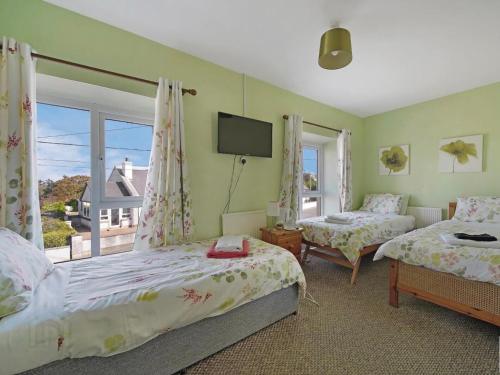 a bedroom with two beds and a tv and a window at ANNORA Bar & Accommodation in Portnoo