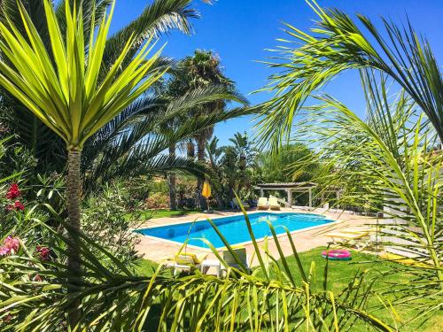 a pool surrounded by palm trees and plants at Elegant villa with sea view in Loulé + private pool in Loulé