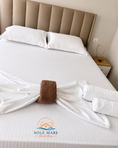 a stuffed animal on a bed with white sheets at Sole Mare - Beach House in Kavajë