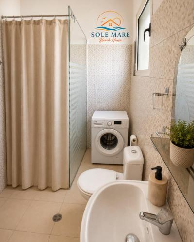 a bathroom with a toilet and a washing machine at Sole Mare - Beach House in Kavajë