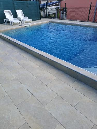 a swimming pool with two chairs next to it at Maison charmante à Petit-Bourg avec piscine partagée in Petit-Bourg