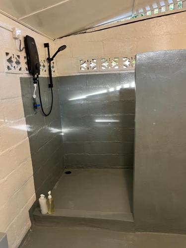 a shower in a bathroom with a phone on the wall at The Nest in Cherating