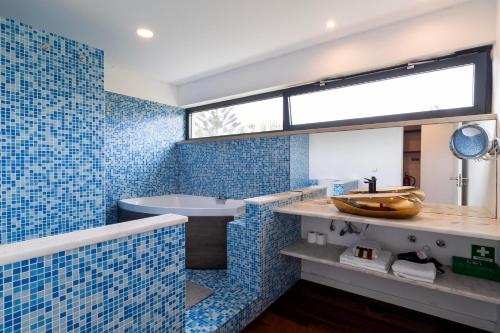 a blue tiled bathroom with a sink and a tub at Penedo Escape Sea Suites in Colares