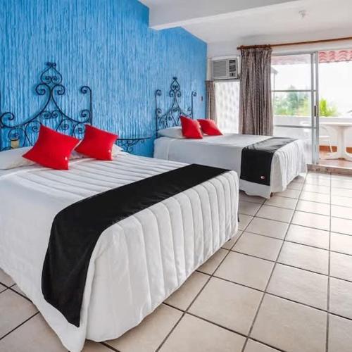 two beds in a room with blue walls and red pillows at CH Paradise Condesa in Acapulco