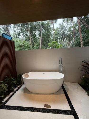 a white bath tub sitting in a bathroom with trees at Villa Manu in Ko Phangan