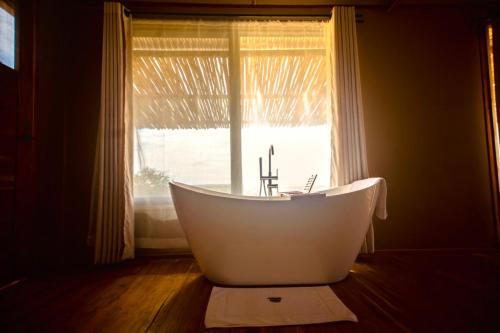 a white bath tub sitting in front of a window at Bushland Luxury Camp in Serengeti