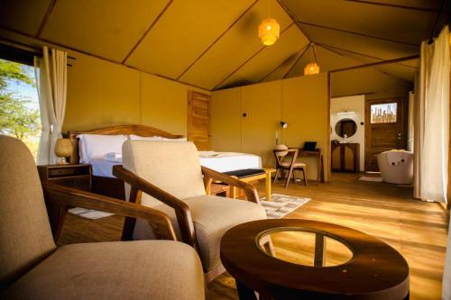 a room with a bedroom with a bed and a table at Bushland Luxury Camp in Serengeti