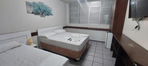 a small room with two beds and a window at FECEP Pousada - 5 minutos a pé da praia in Guaratuba