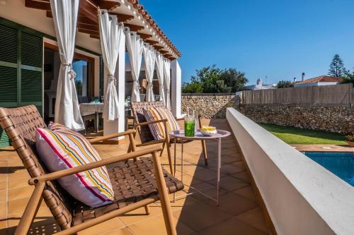 a patio with chairs and a table with umbrellas at Elegant Villa in Ciutadella de Menorca with Private Pool in Sa Caleta