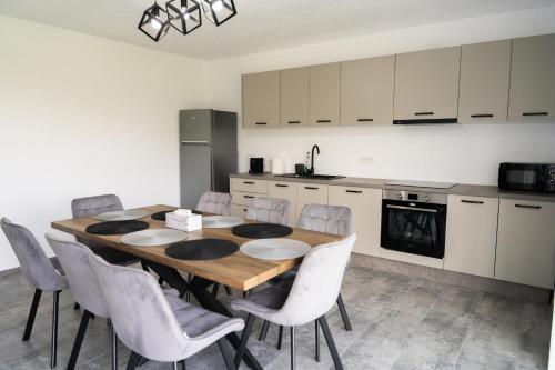 a kitchen with a wooden table and white chairs at Casa Andrei Guesthouse in Bărăşti