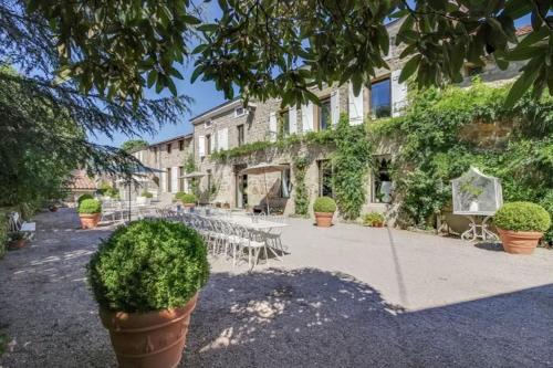 a building with tables and chairs in front of it at Manoir majestueux à Satillieu avec piscine privée in Satillieu